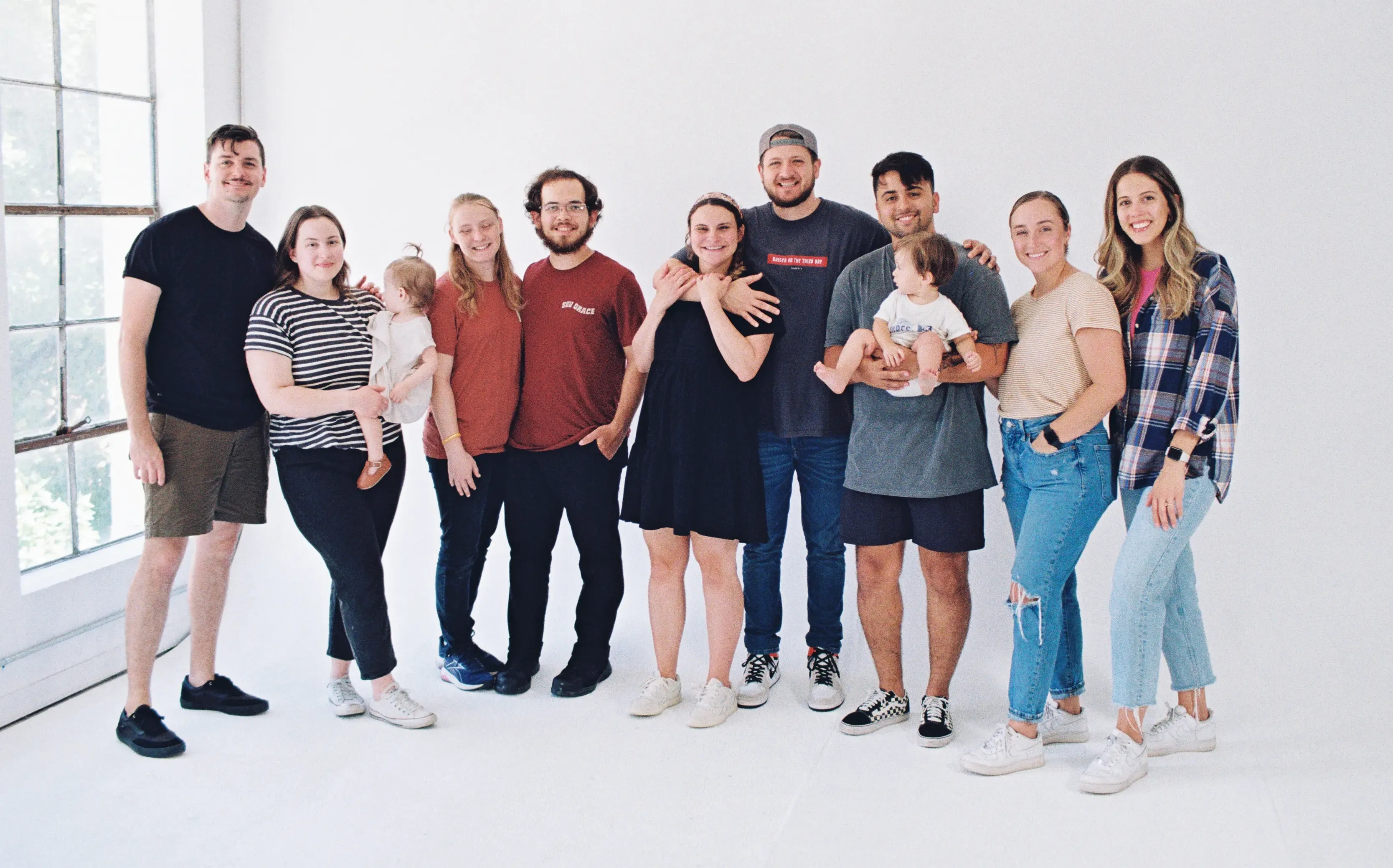 A group of several freelancers pose in front of a white studio wall